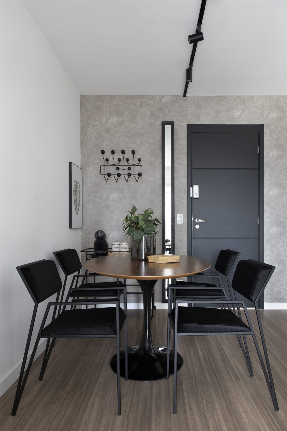 Sala de jantar de apartamento alugado com mesa redonda de madeira, cadeiras pretas e porta grafite, projeto INSIDE