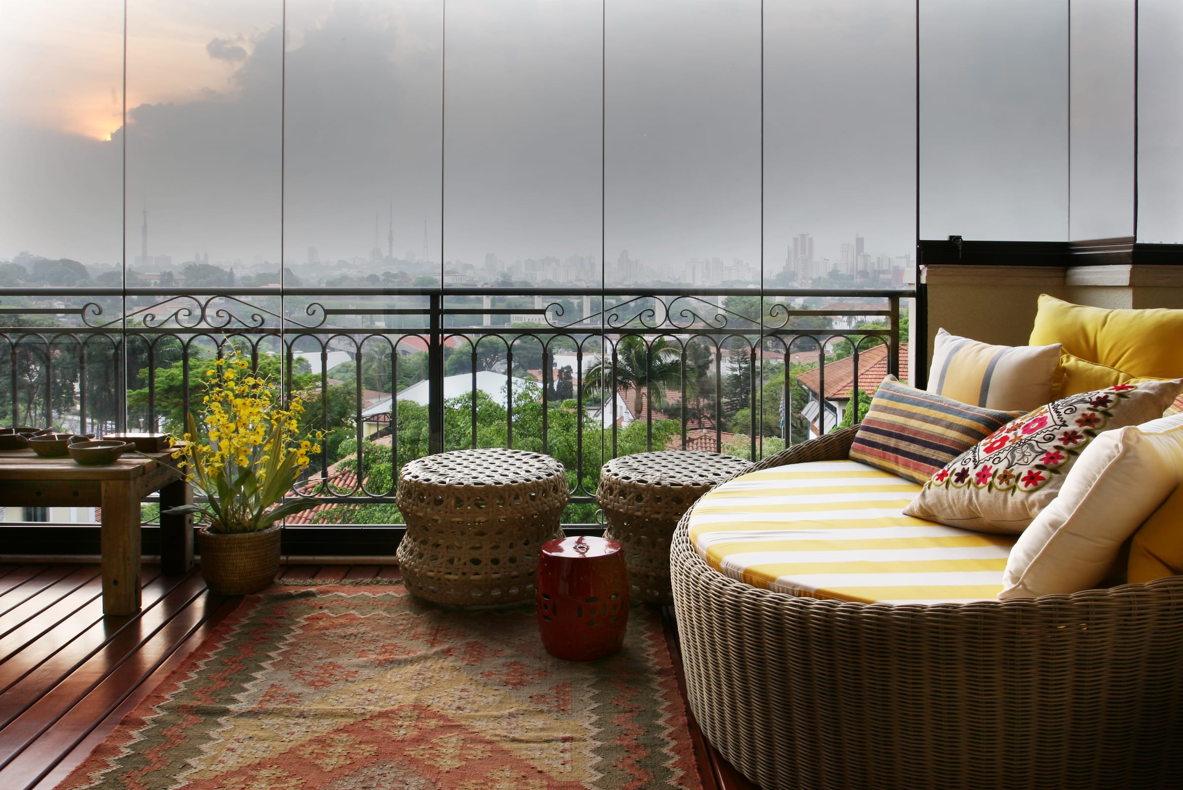 Rosa Albuquerque: a varanda envidraçada com o skyline de São Paulo ao fundo, daybed listrado e kilim, acervo INSIDE