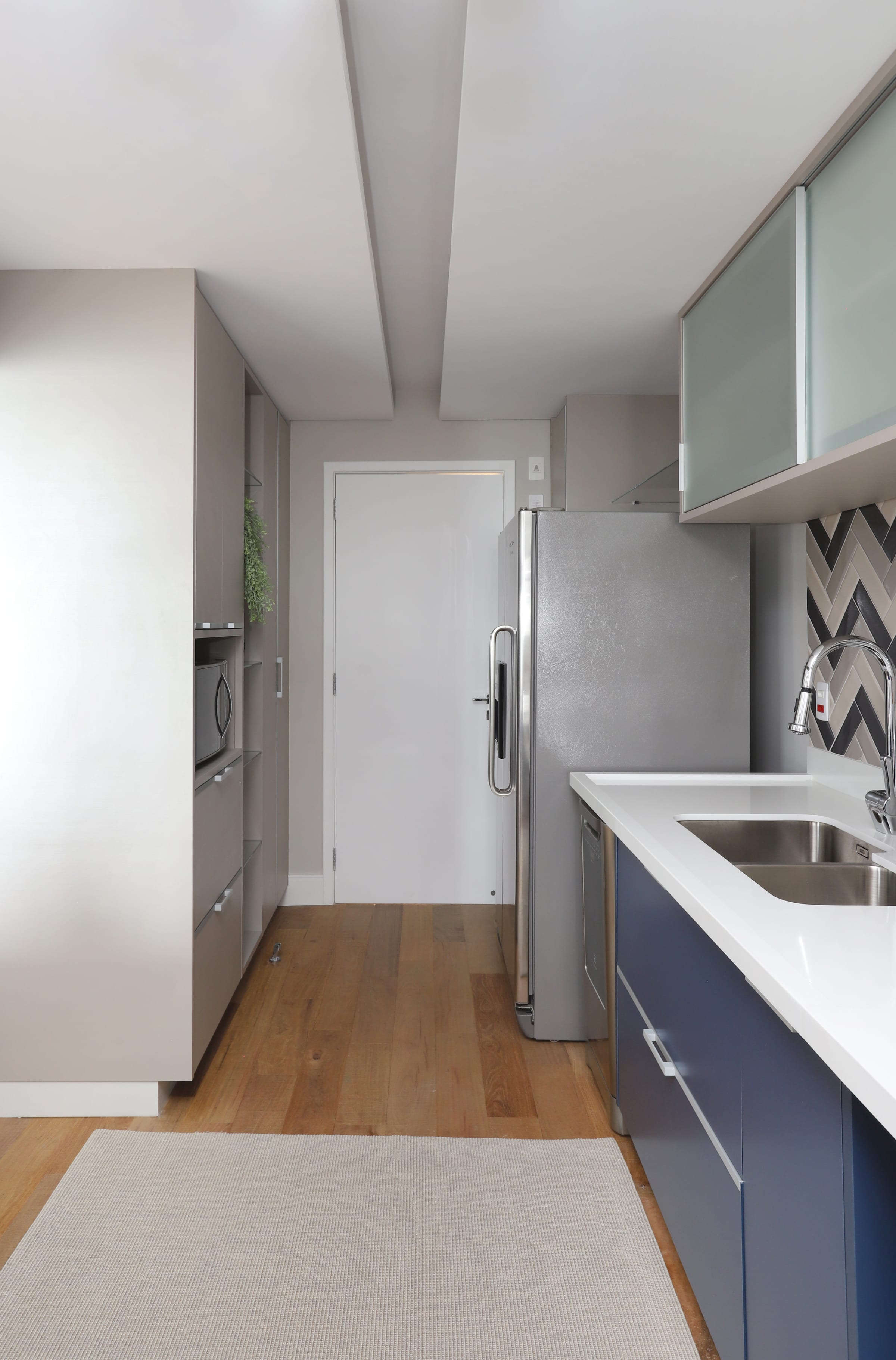 Estar de varanda com sofá branco, luminárias pendentes pretas, tapete azul e plantas em vaso, projeto INSIDE