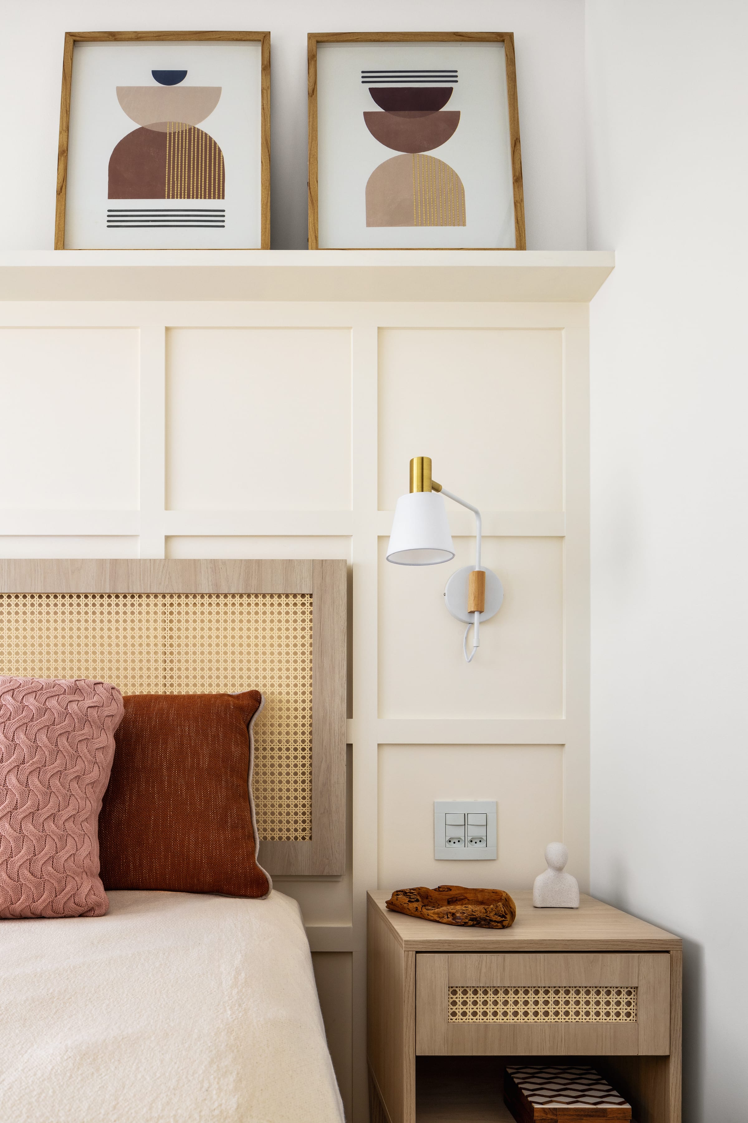 Quarto de casal com cabeceira em palha cana, abajur dourado, cama em tom creme e painel de lambri neutro, projeto INSIDE